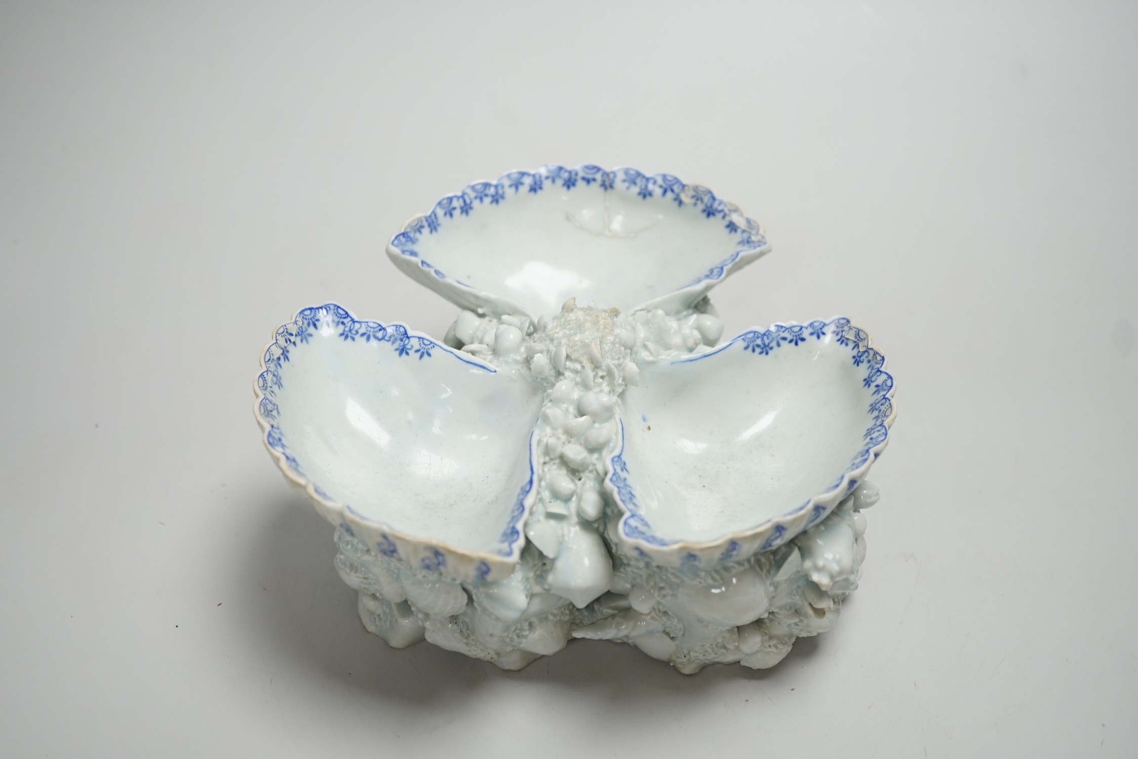 An early Bow porcelain three shell salt, the naturalistically modelled shells picked out in underglaze blue, on a shell and coral encrusted base, 8cm high